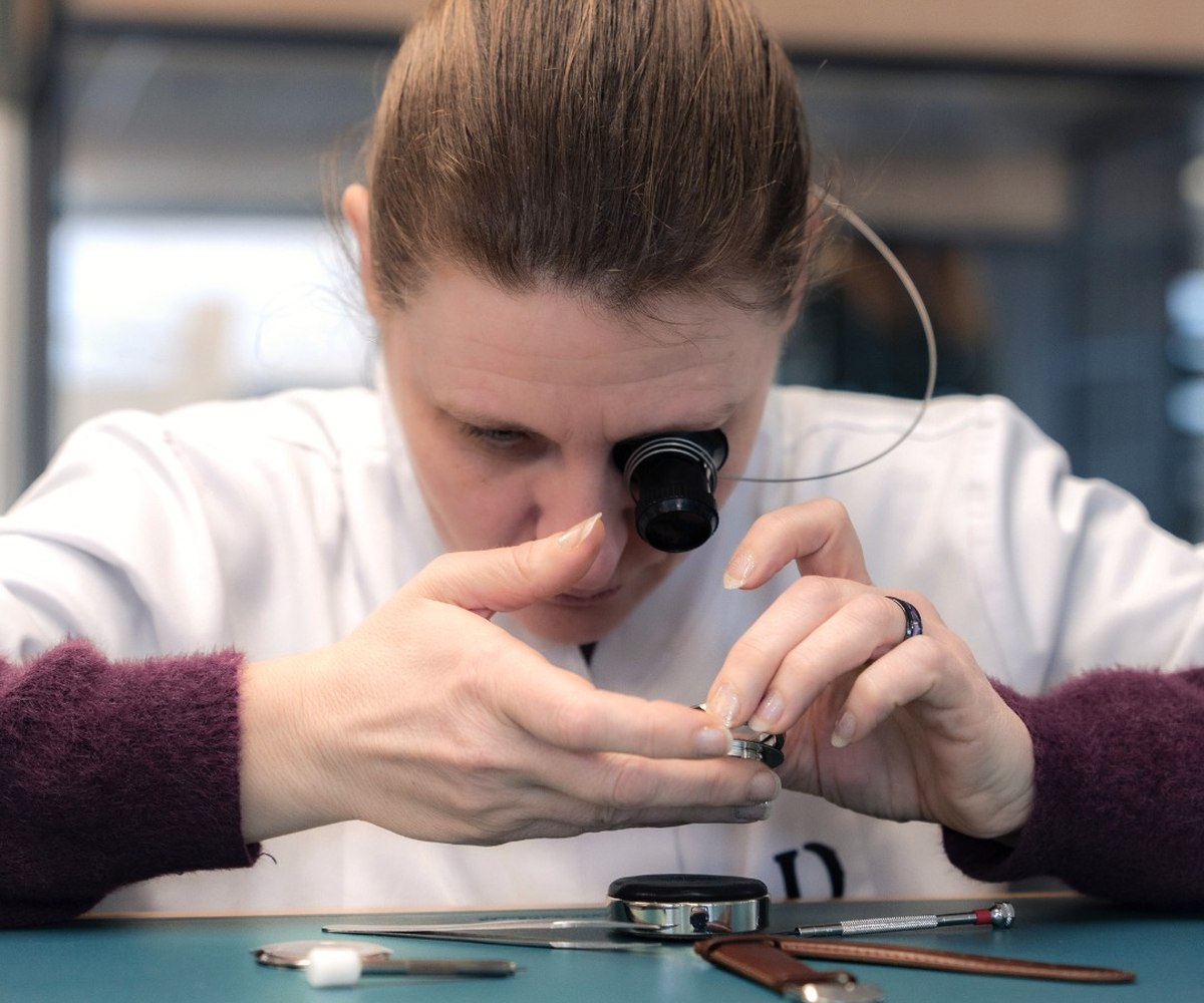 A watchmaker examining a movement with a magnifying glass