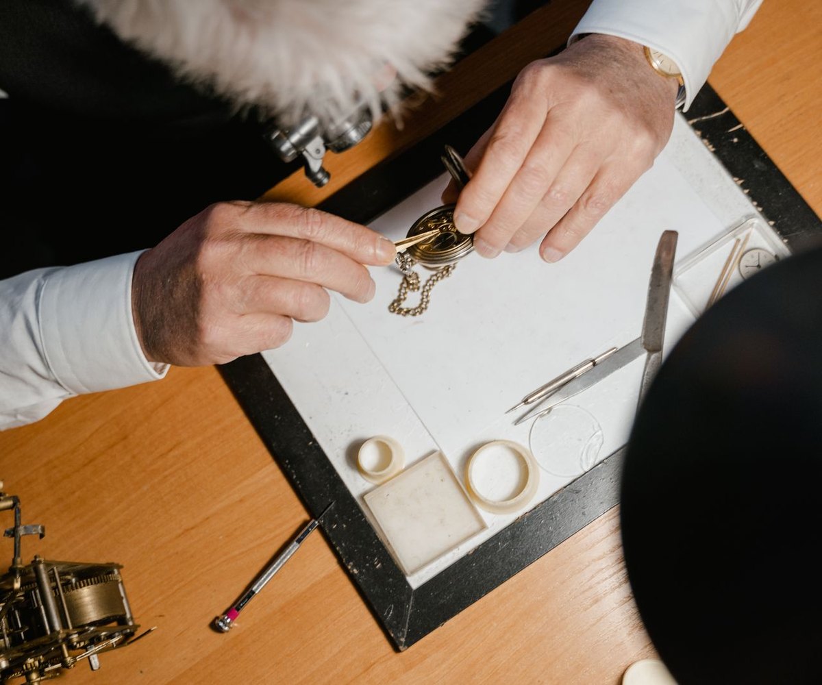 Watchmaker's hands and precision tools on a workbench