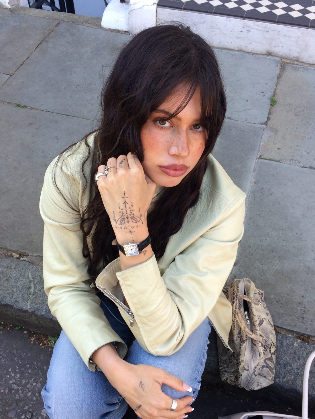Femme en veste creme assise dans la rue portant une Casio vintage
