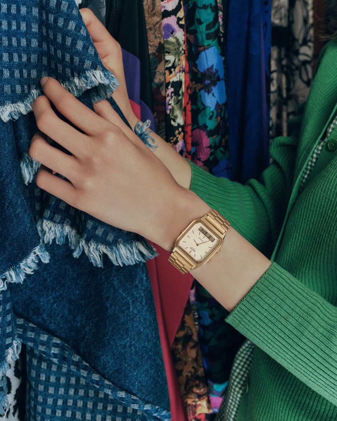 Femme en pull vert dans une friperie portant une Casio doree