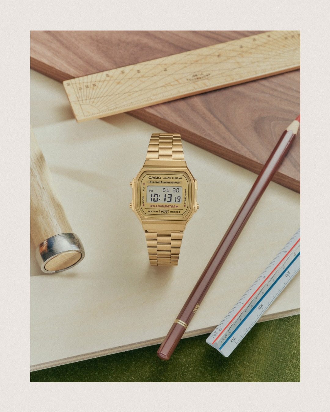 Montre Casio doree vintage posee a plat avec des objets d'ete