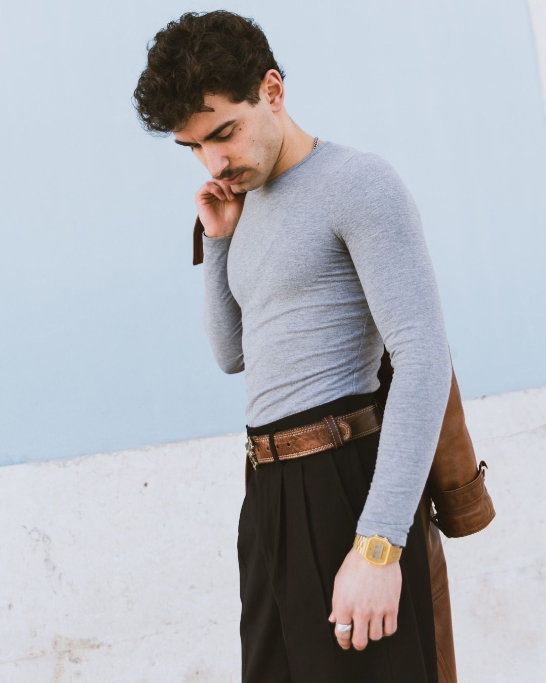 Homme au telephone devant un mur bleu portant une Casio doree