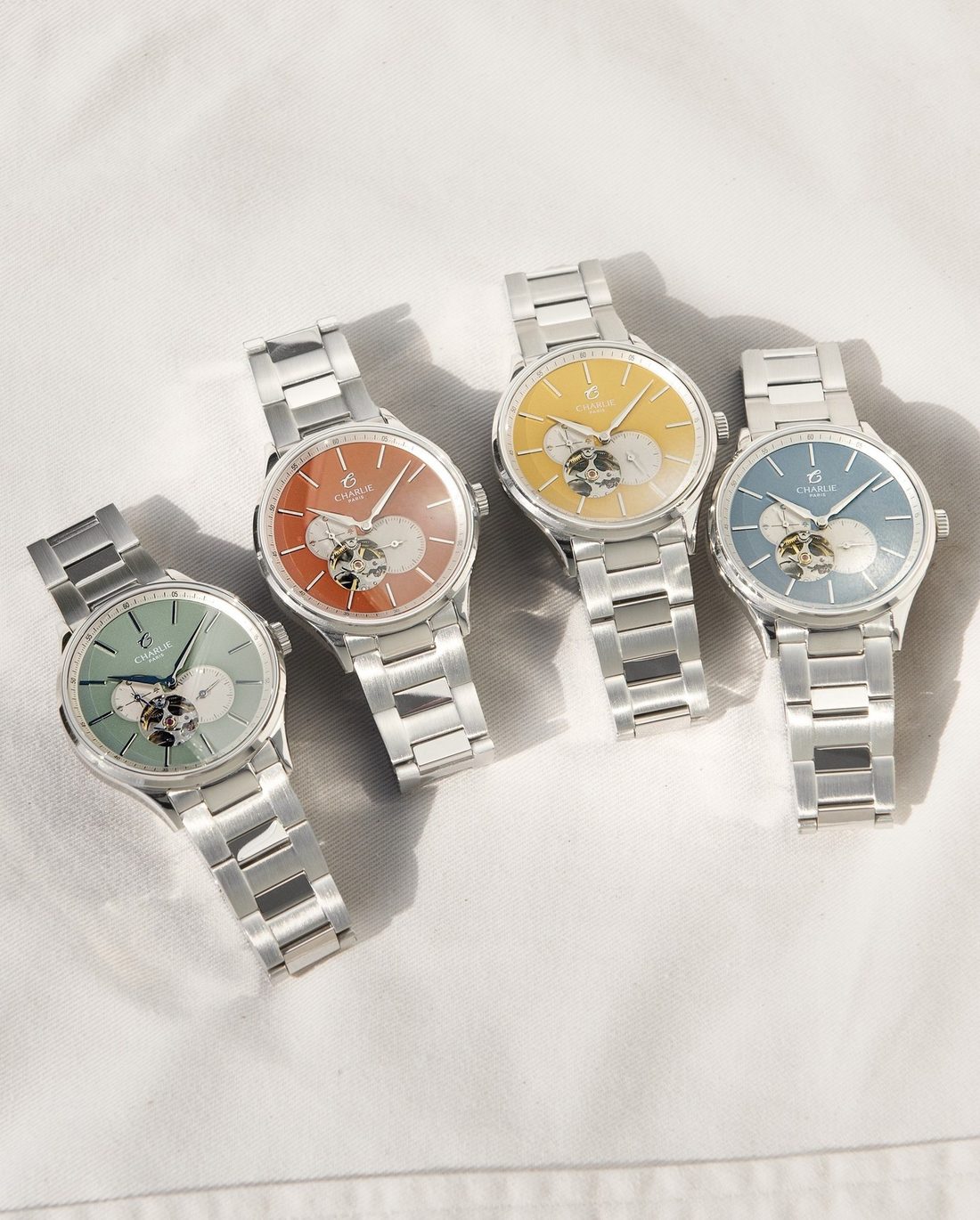 Quatre montres Charlie Paris coeur ouvert aux cadrans colores posees au soleil
