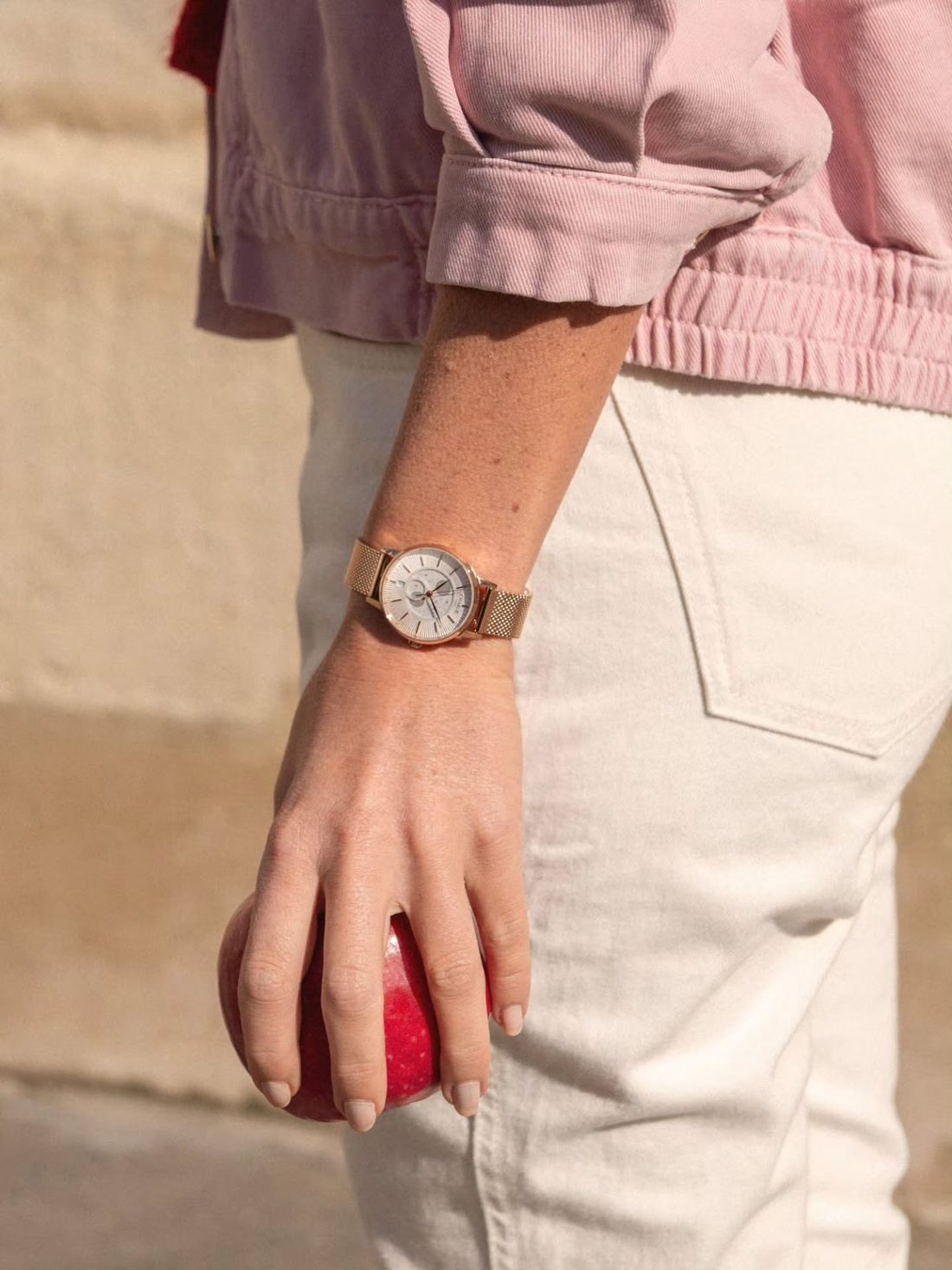 Montre Charlie Paris doree au poignet, veste rose et jean blanc