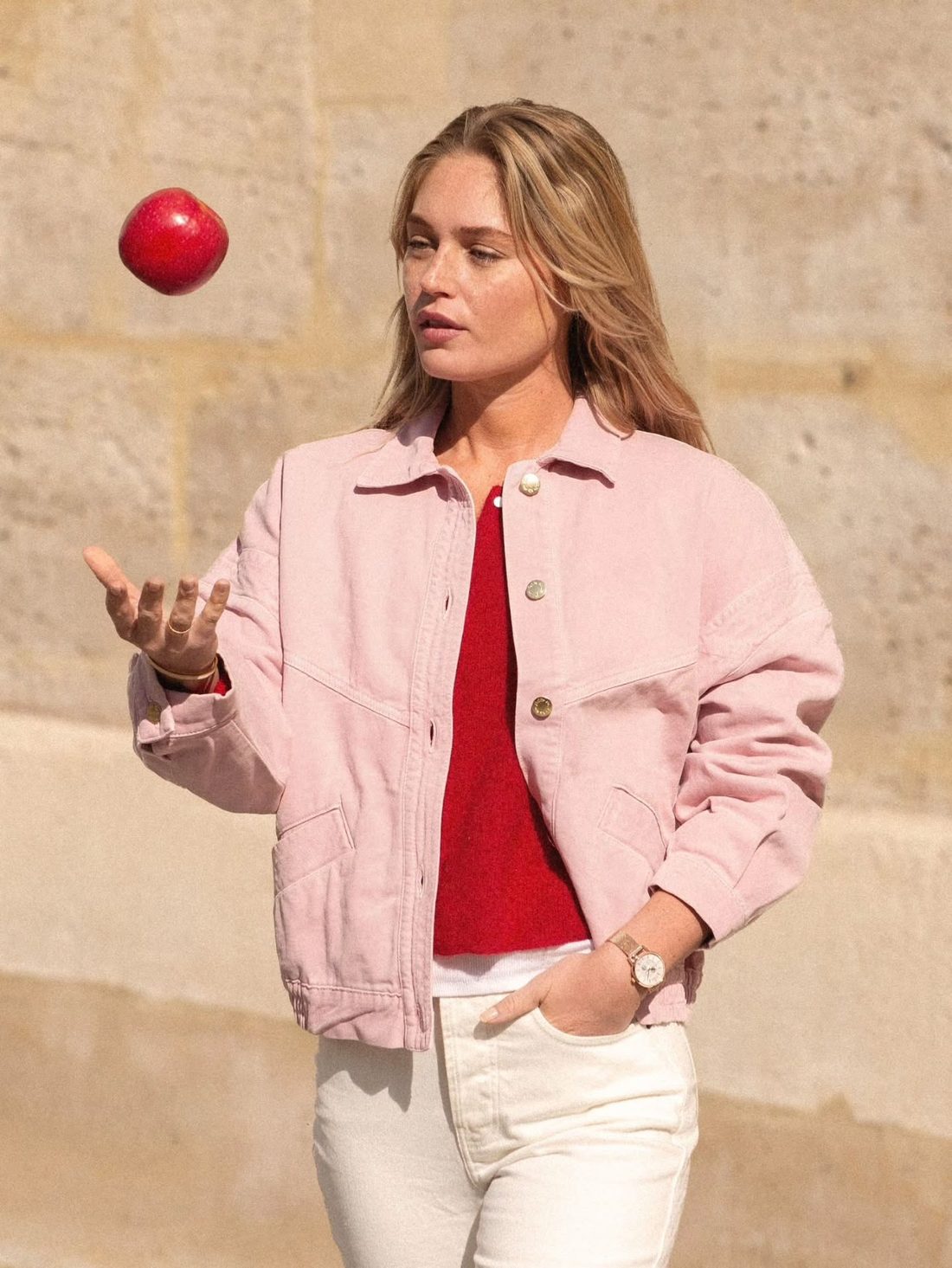 Femme en veste rose jonglant avec une pomme, montre Charlie Paris au poignet