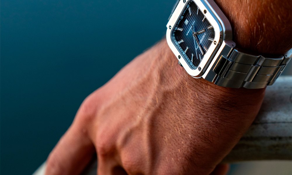 Montre en acier portee au poignet au bord de l'eau, couronne vissee avant la baignade
