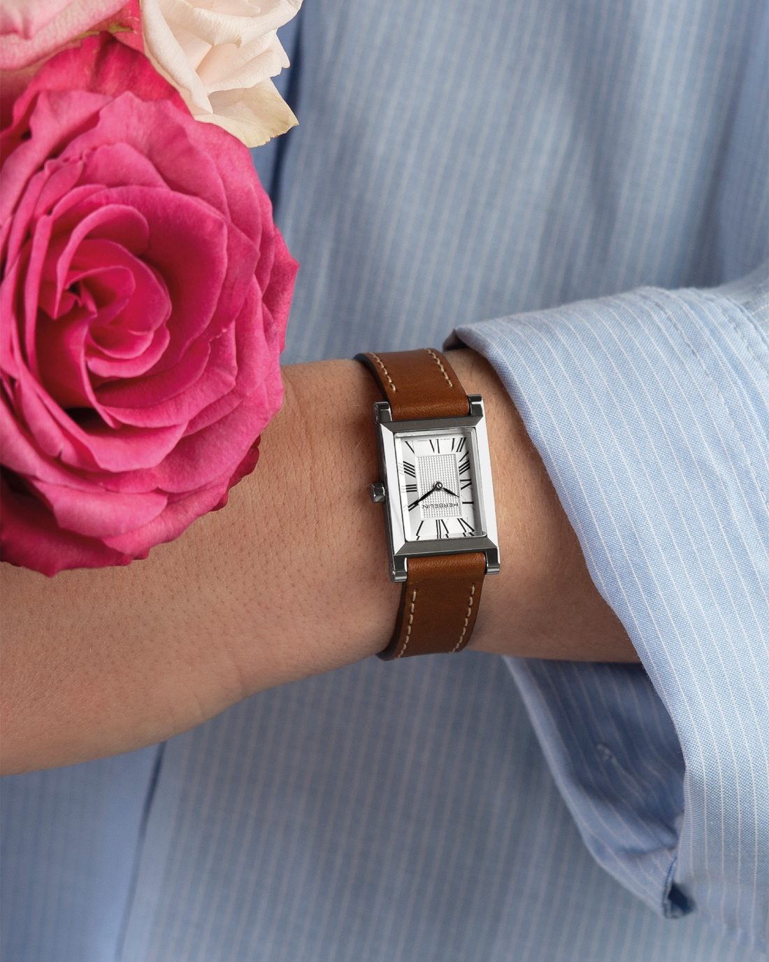 Montre Michel Herbelin rectangulaire au poignet avec une rose fuchsia
