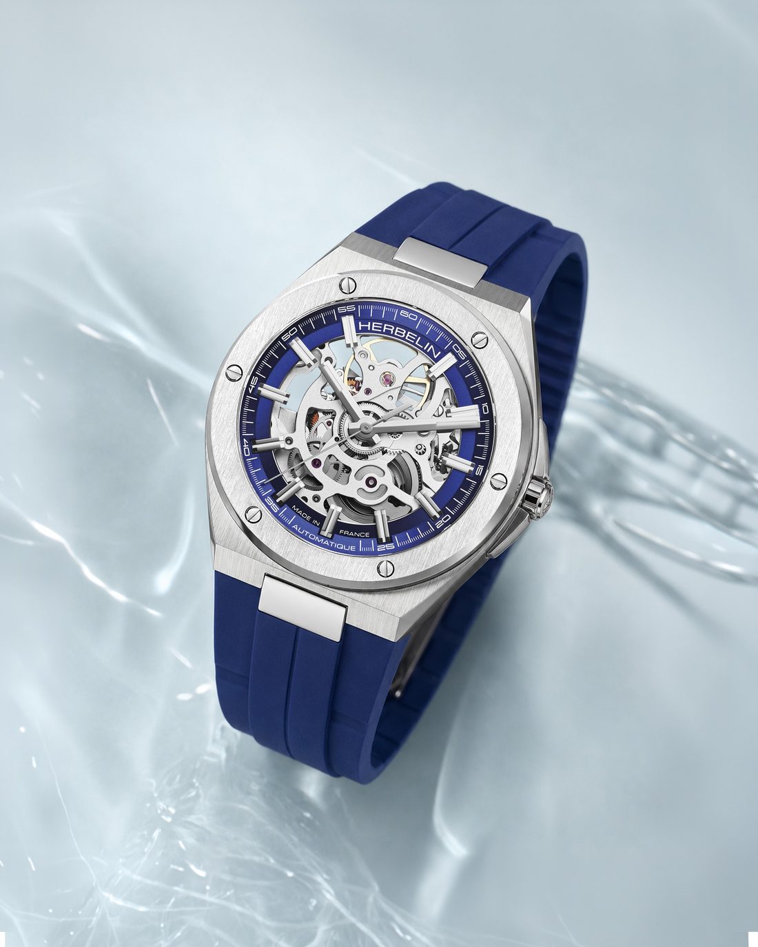 Montre Michel Herbelin squelette bleue sur bracelet caoutchouc posee sur l'eau