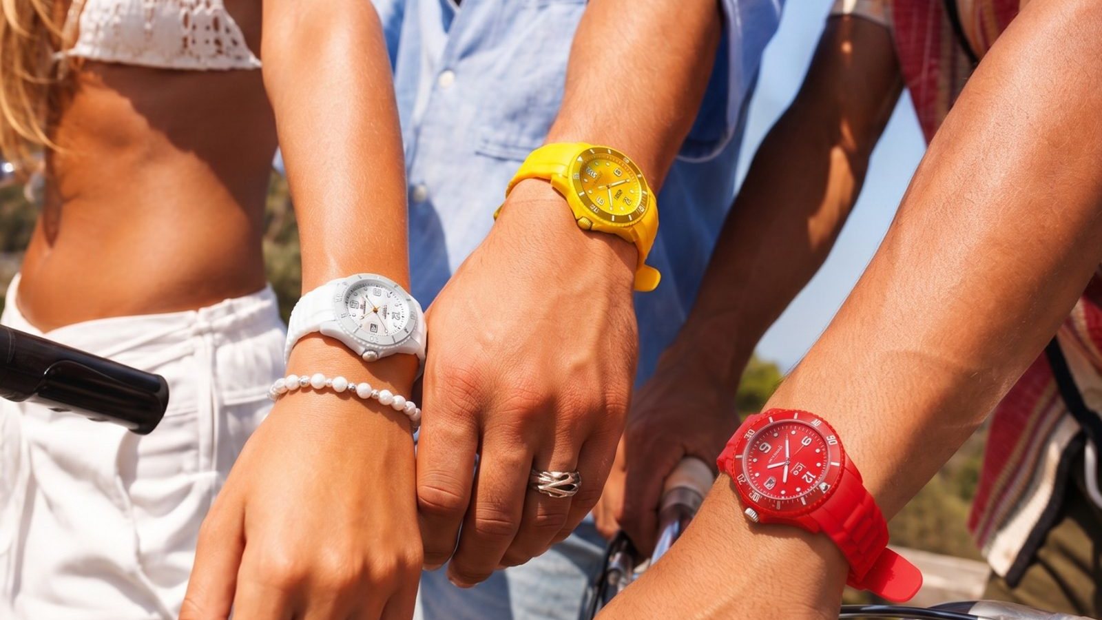 Trois amis portant des montres Ice-Watch colorees sous le soleil d'ete