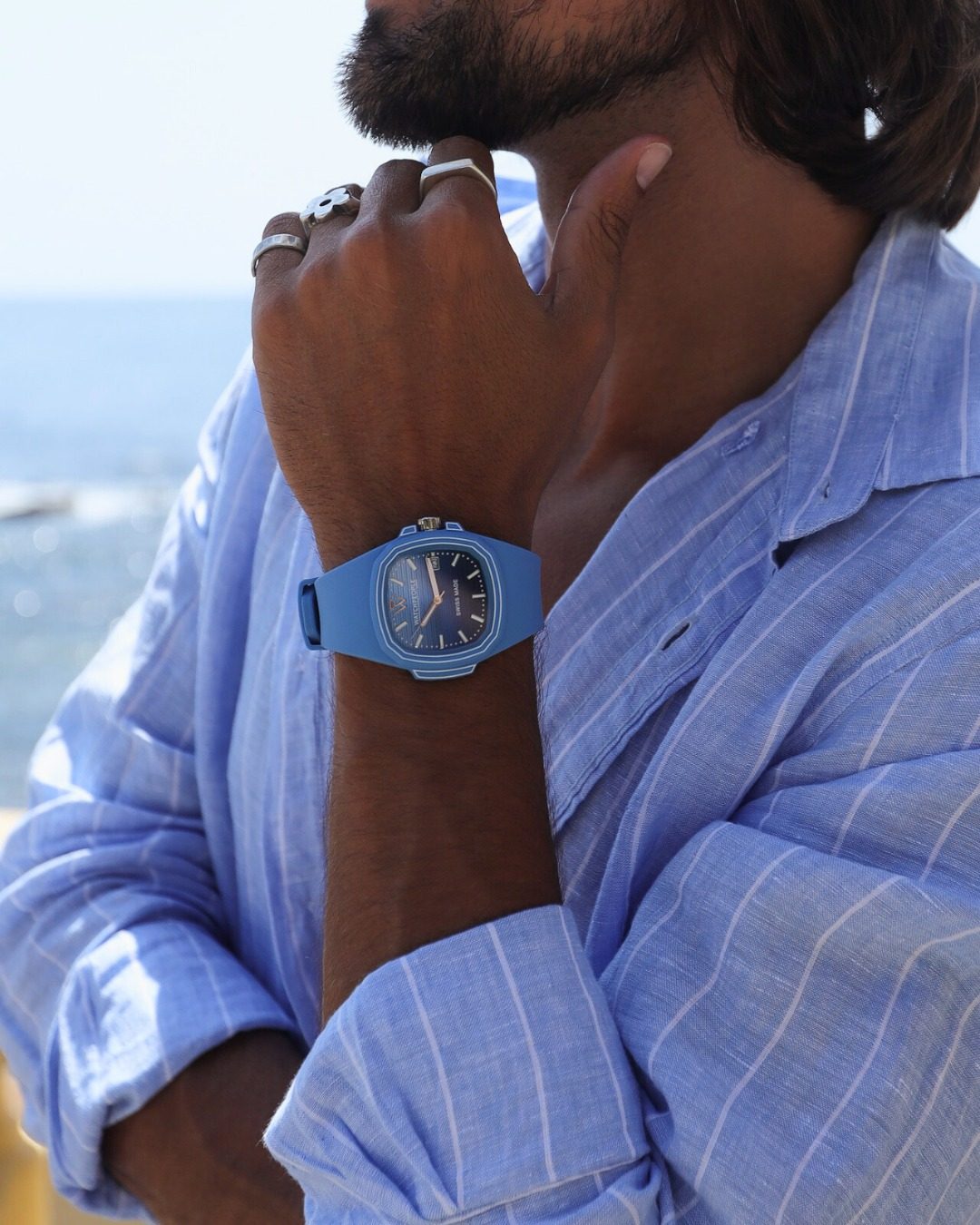 Homme en chemise de lin bleue au bord de la mer portant une montre Ice-Watch bleue