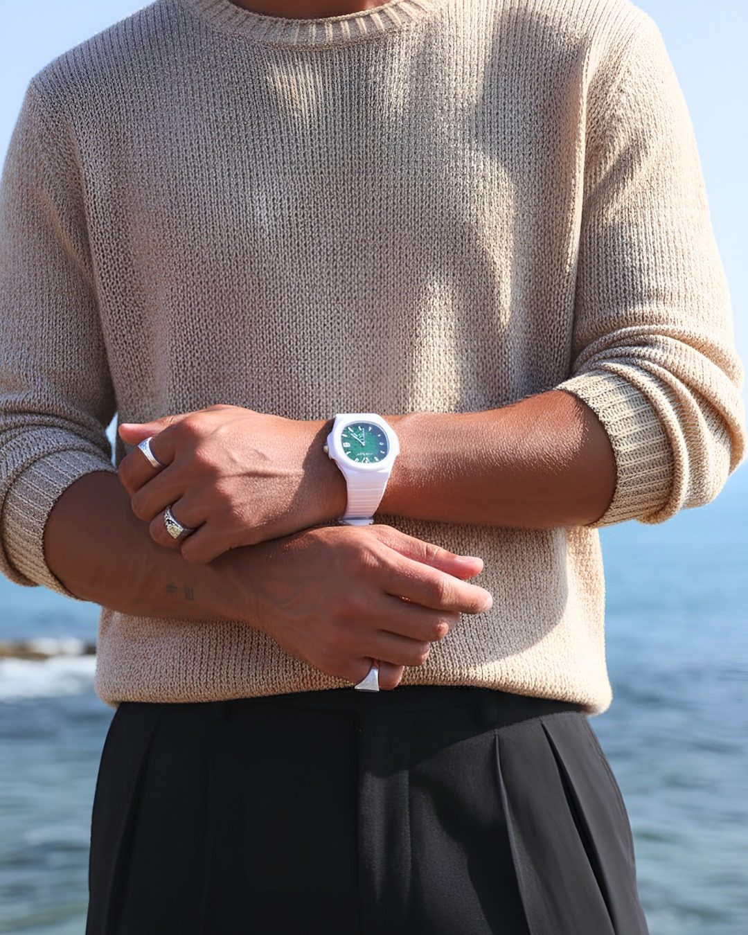 Homme en pull ecru au bord de la mer portant une montre Ice-Watch blanche