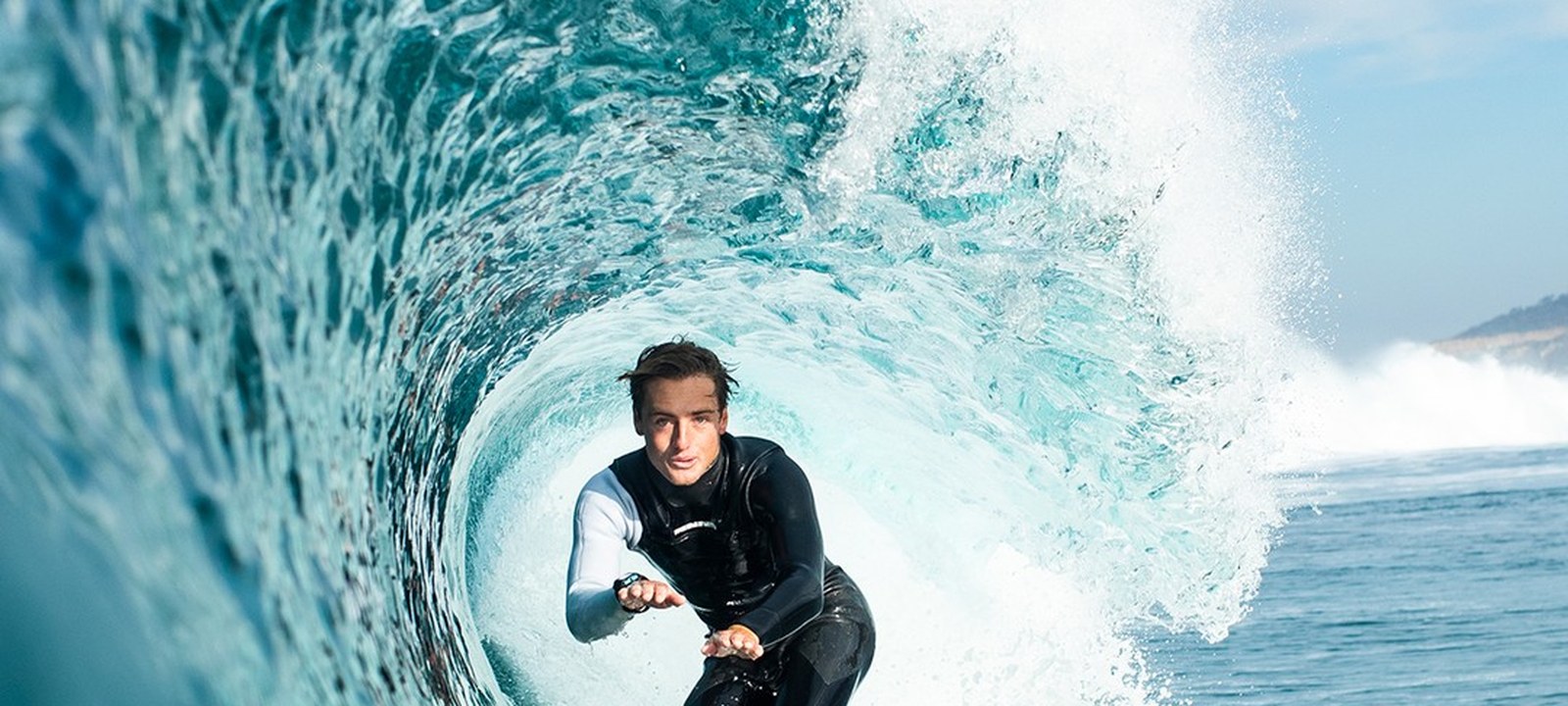 Surfeur dans le tube d'une vague, montre Nixon au poignet