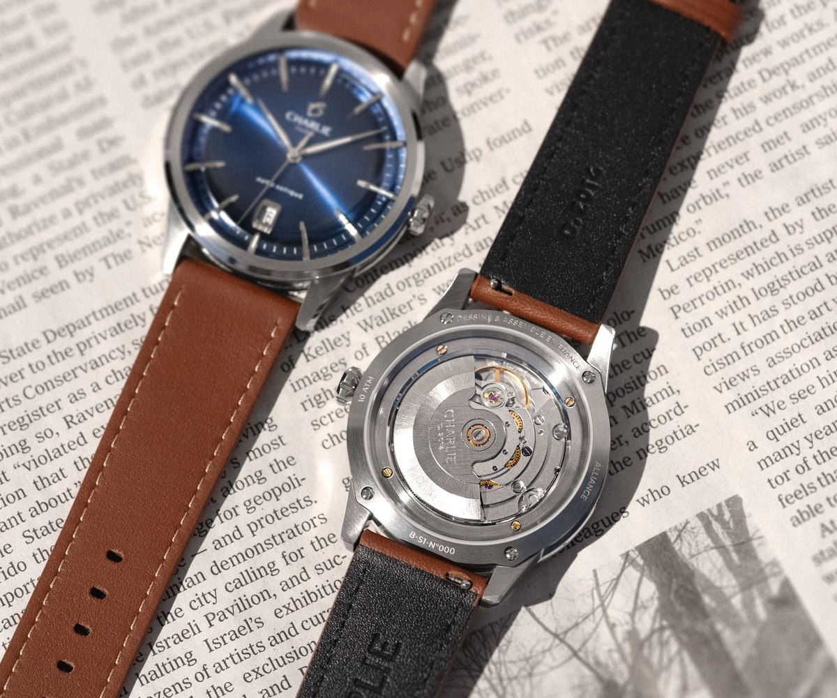 Montre Charlie Paris a bracelet de cuir marron et cadran bleu, posee sur un journal