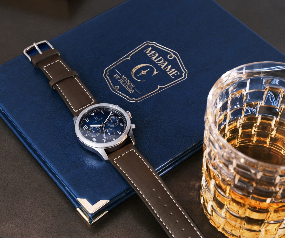 Chronographe Pierre Lannier sur bracelet de cuir marron, pose sur un carnet bleu