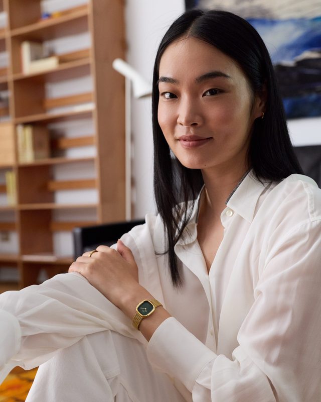 Femme en chemise blanche, montre Daniel Wellington cadran vert