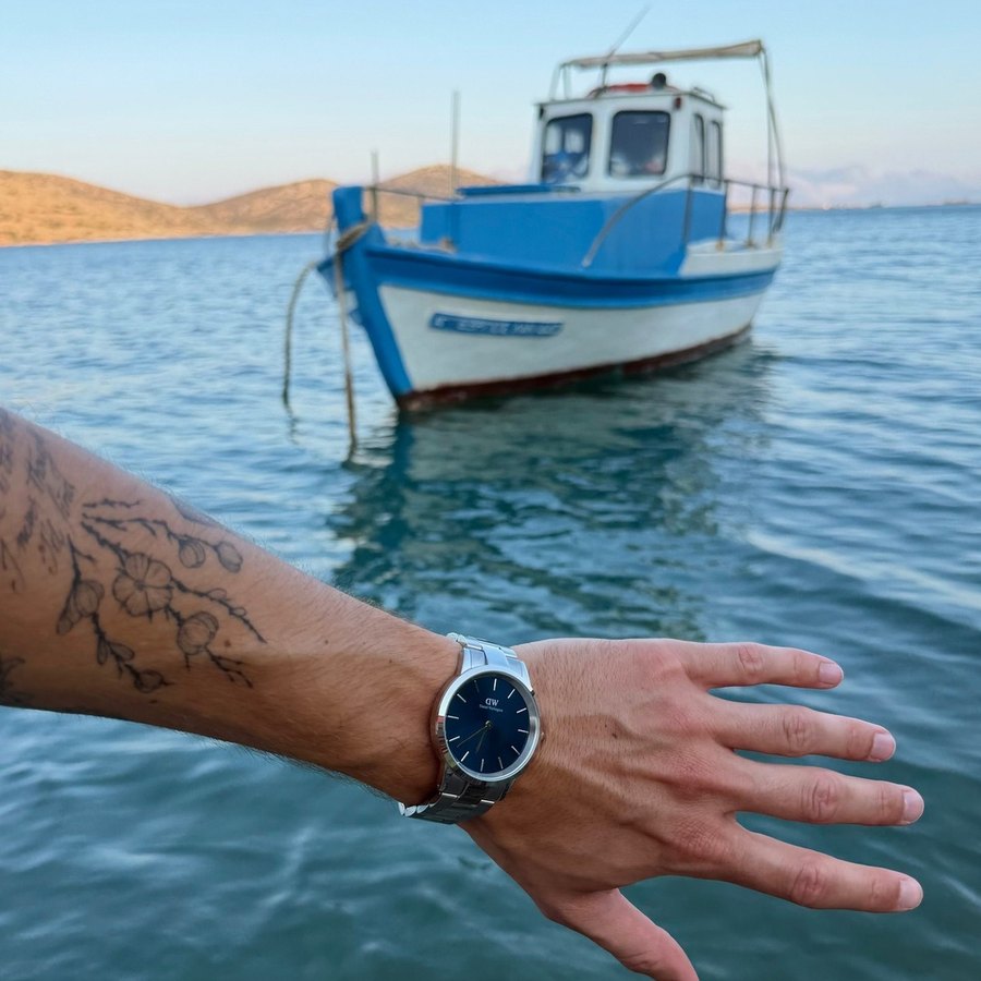 Daniel Wellington, main tendue vers un bateau bleu
