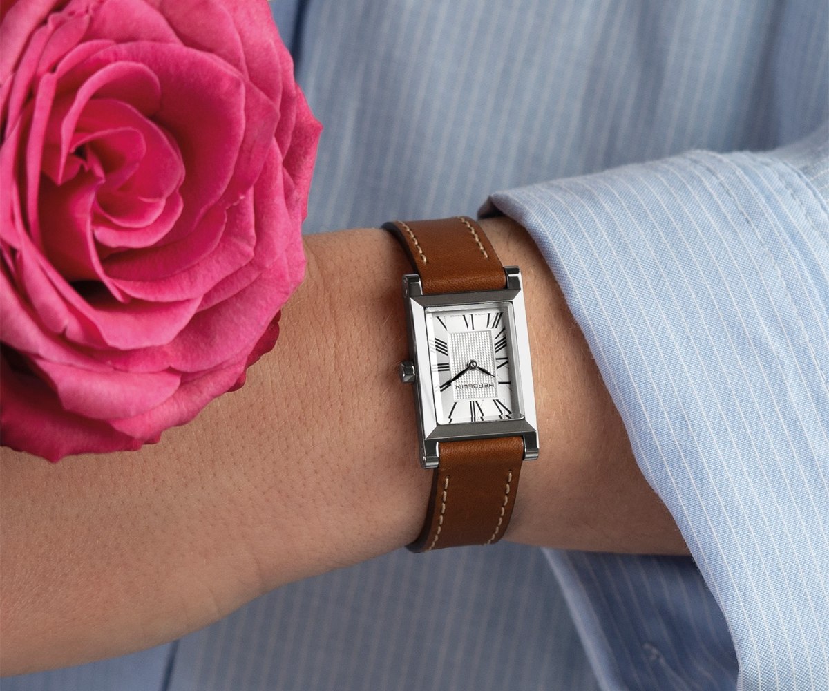 Montre rectangulaire Michel Herbelin portée au poignet, près d'une rose