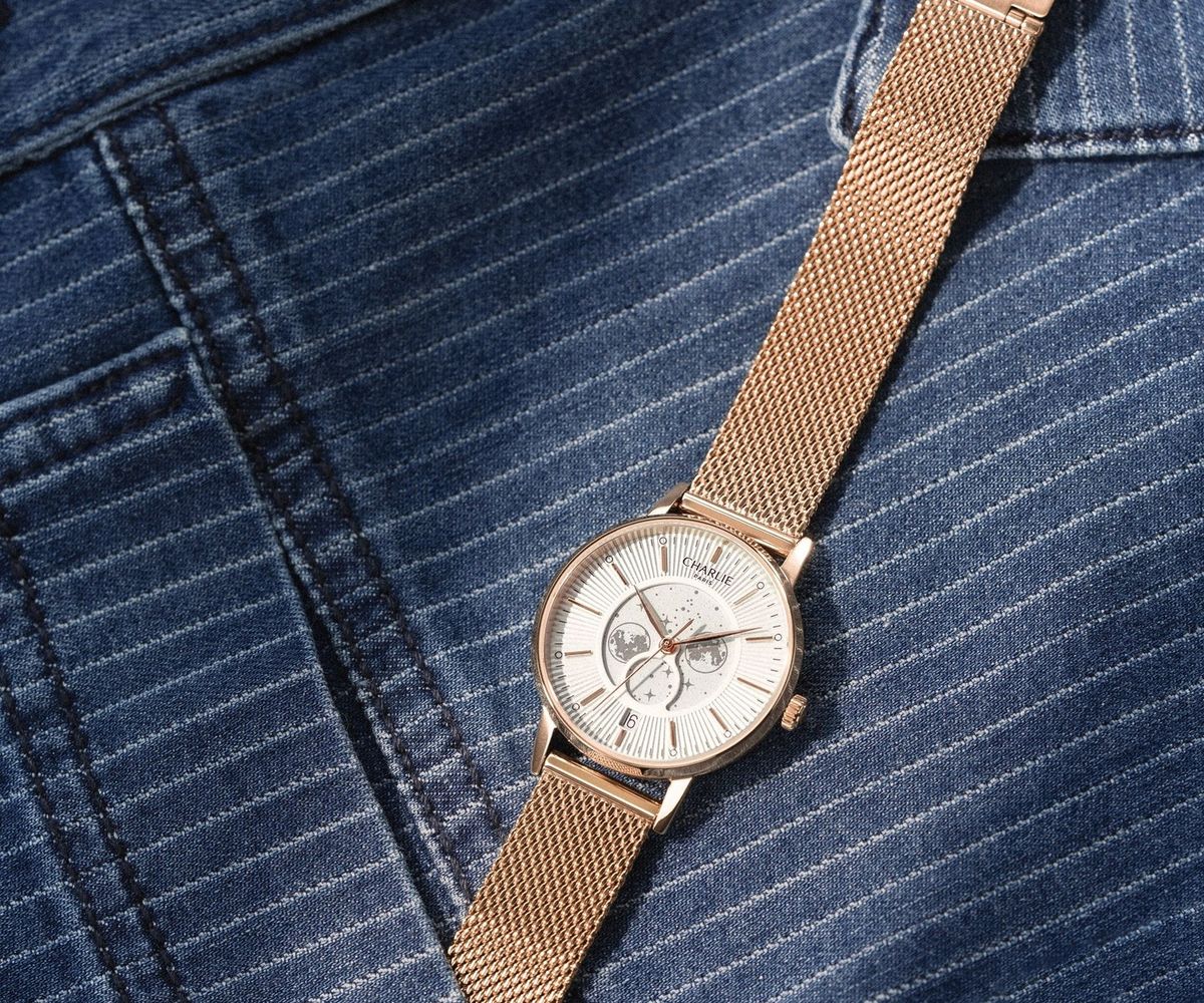 Montre Charlie Paris dor&eacute;e rose sur maille milanaise pos&eacute;e sur un tissu ray&eacute;