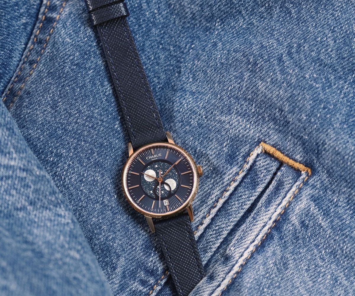 Montre Charlie Paris dorée rose cadran phase de lune posée sur une poche de jean