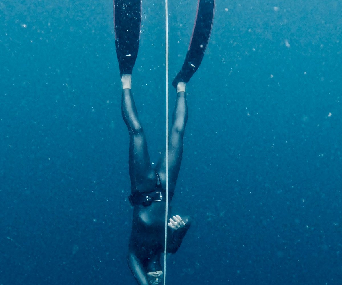 Apneiste descendant le long d'un cable dans l'eau profonde