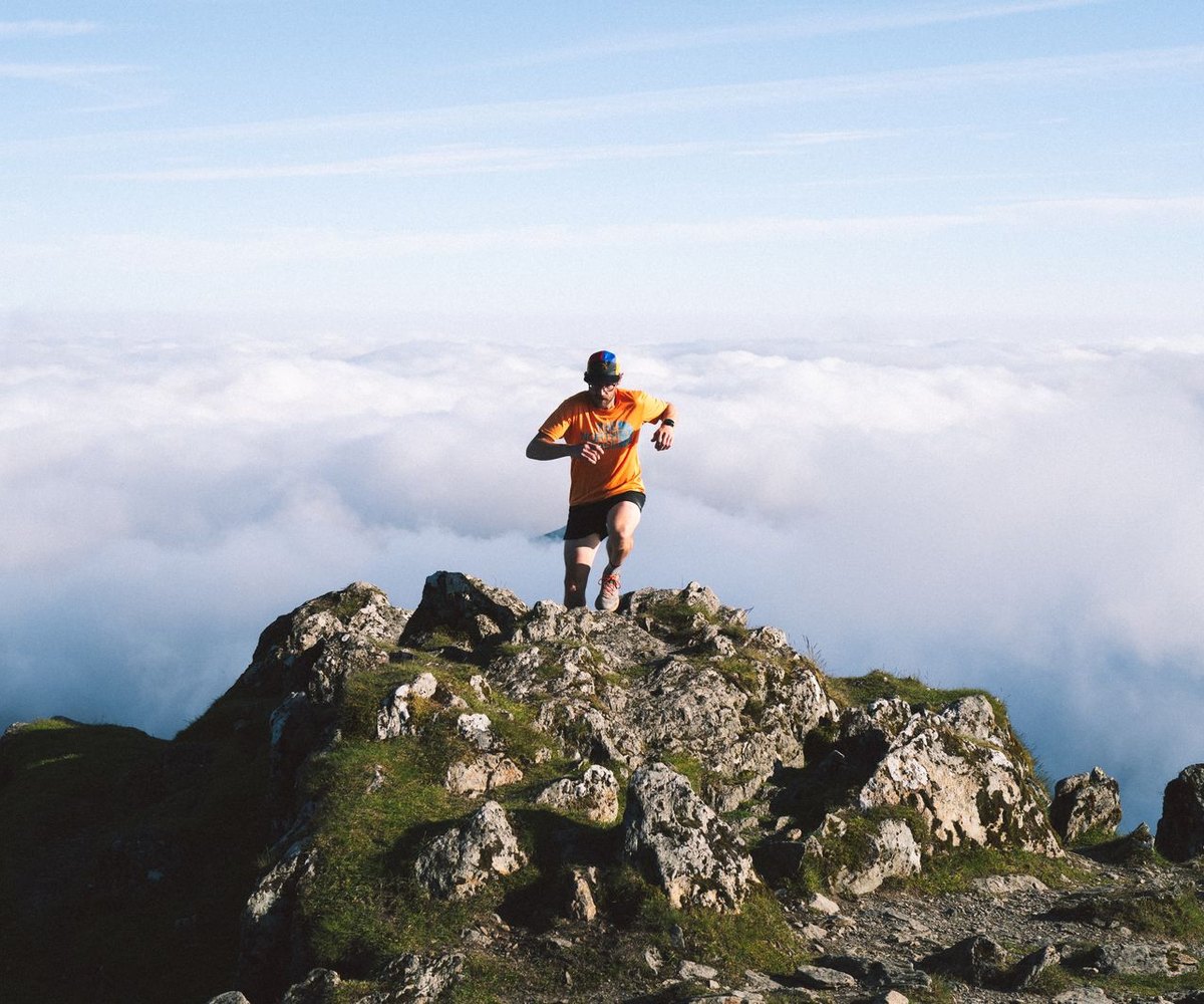 Coureur au sommet d'un rocher au-dessus des nuages