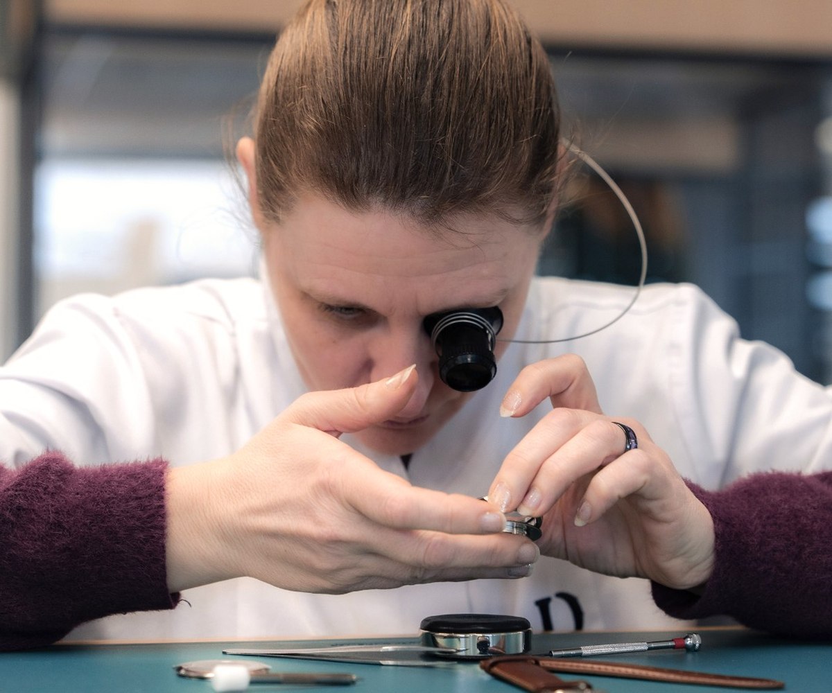 Horlogère à la loupe travaillant sur un mouvement squelette