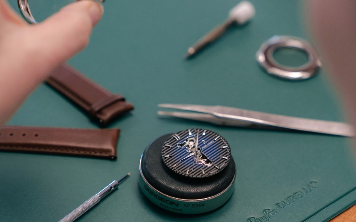 Mouvement squelette et outils d'horloger sur un &eacute;tabli vert