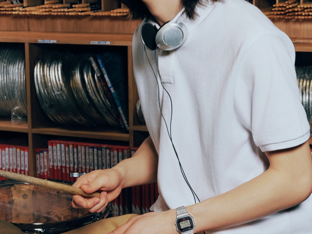 Jeune homme au casque devant un bac a vinyles, montre digitale acier au poignet