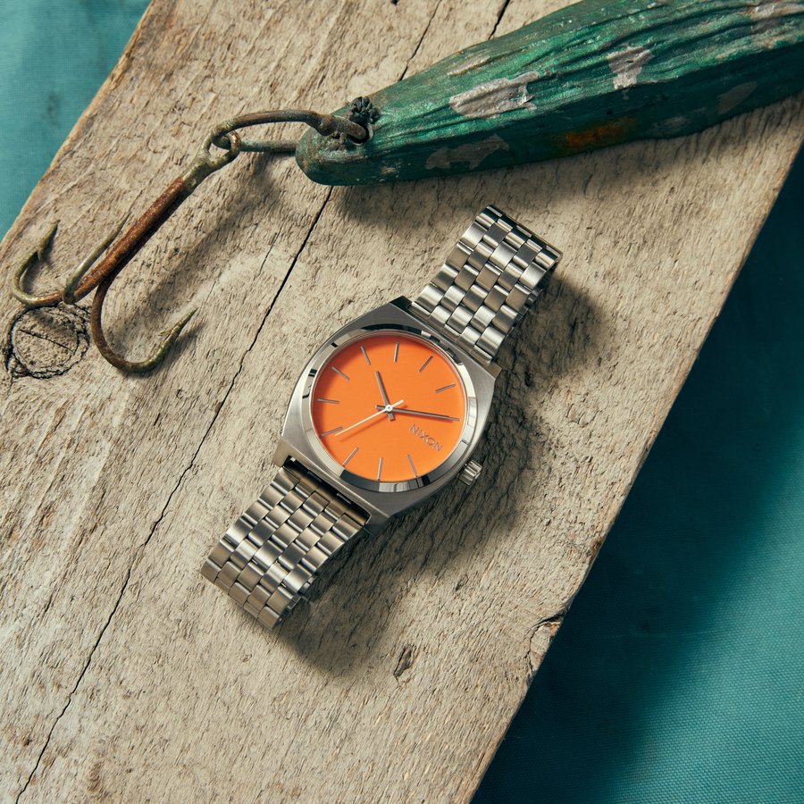 Montre Nixon Time Teller &agrave; cadran orange pos&eacute;e sur du bois flott&eacute;