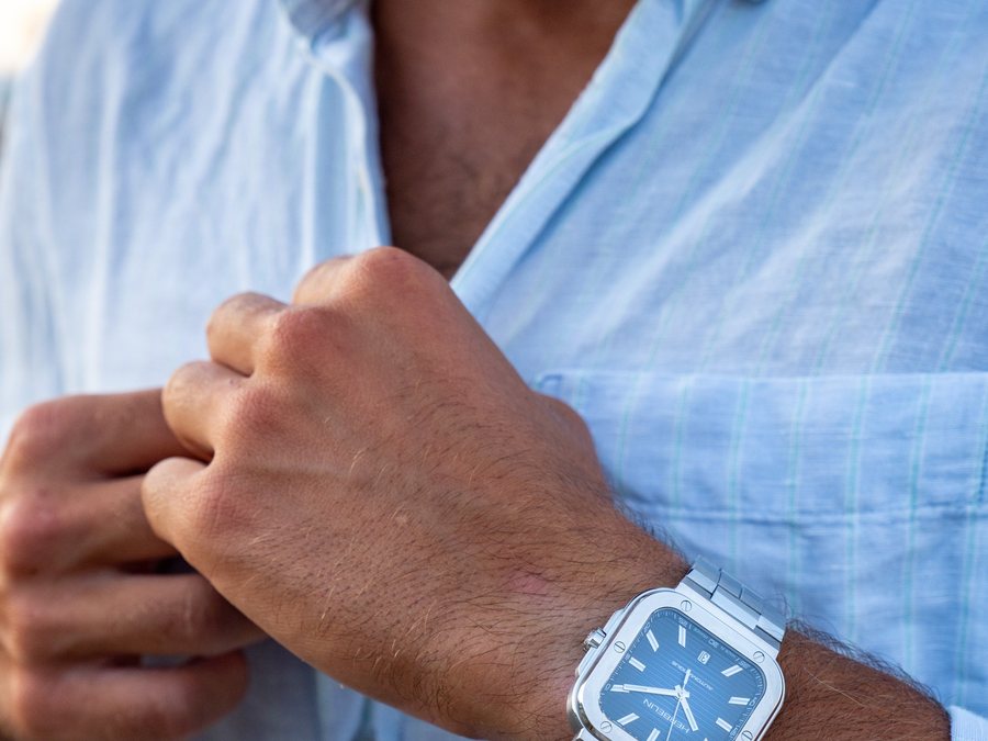 Montre carr&eacute;e cadran bleu au poignet, chemise bleue
