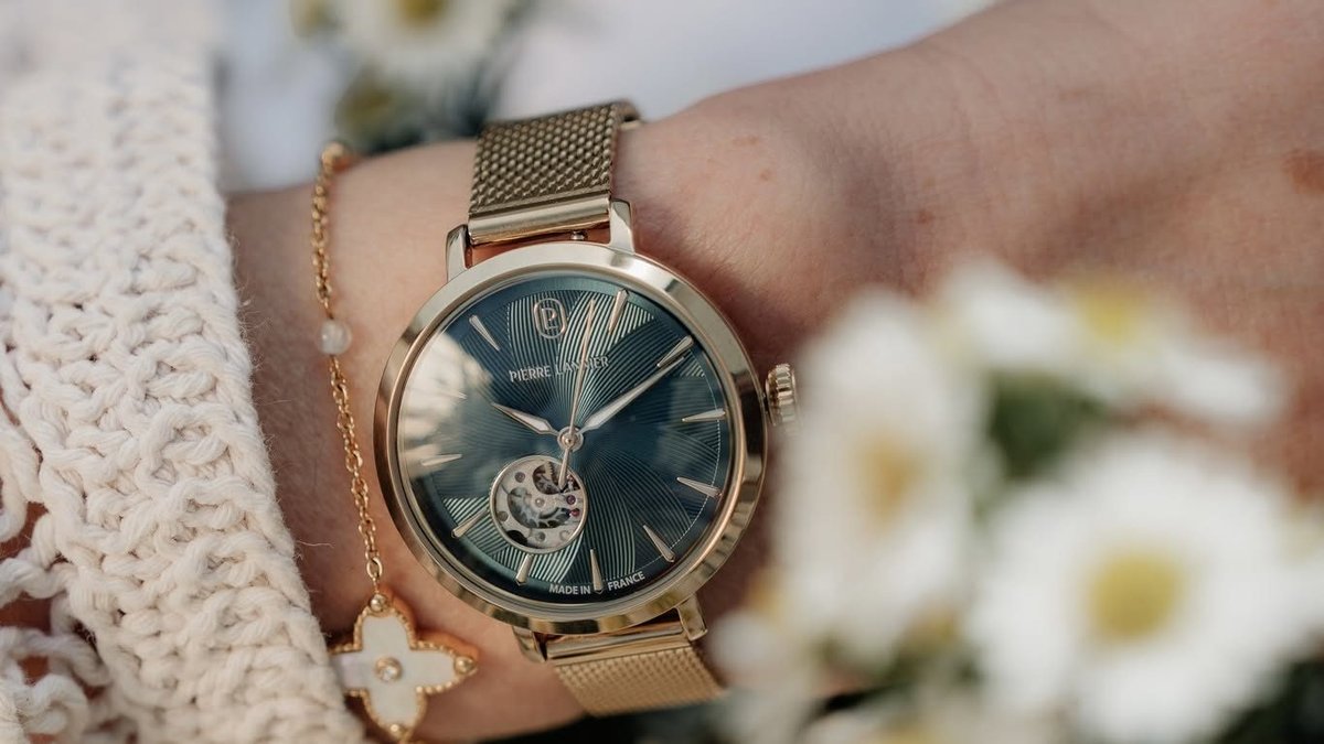 Unique gold open-heart women's watch worn on the wrist amidst a bouquet of daisies