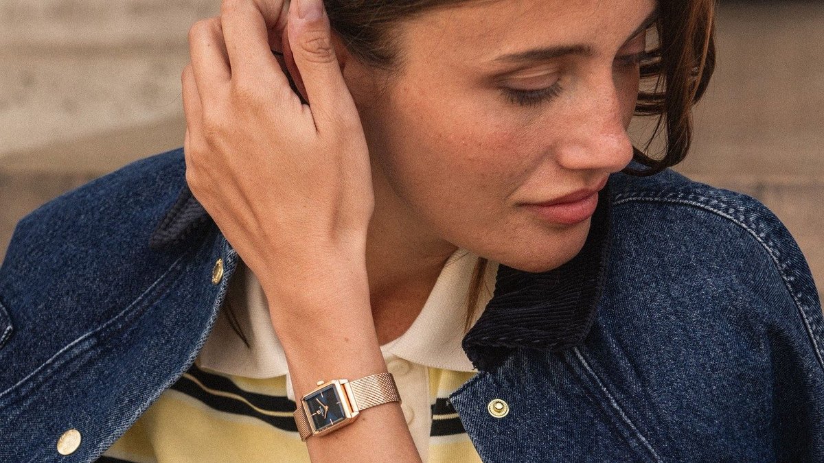 Unique rectangular rose gold women's watch worn with a denim jacket