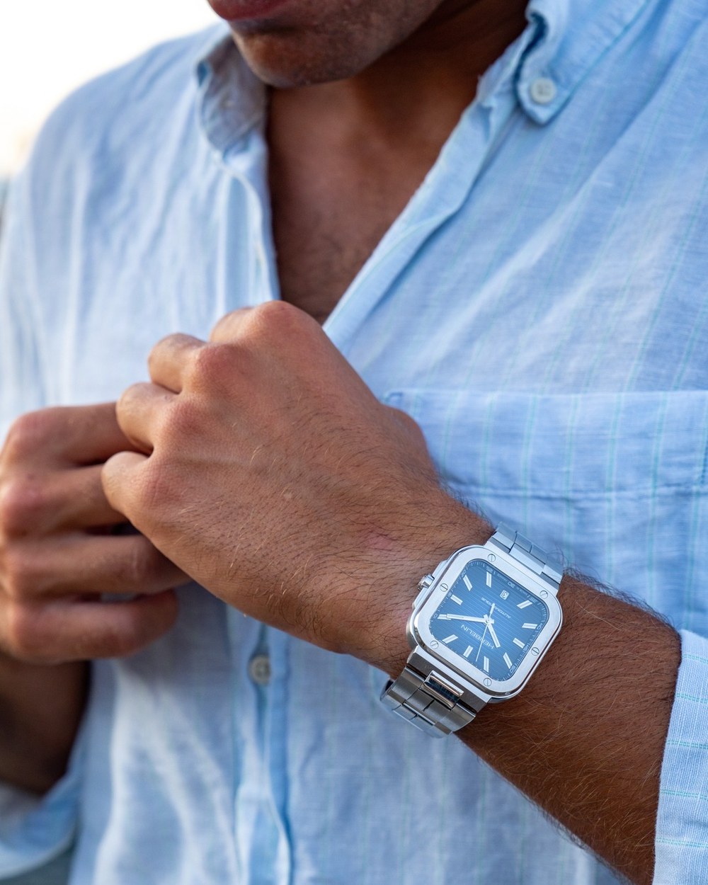 A blue shirt cuff with a steel watch
