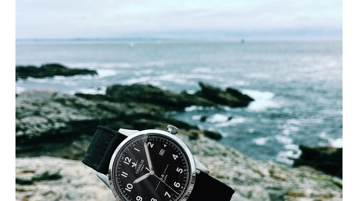 Montre Charlie Paris posée sur un rocher face à la mer en été