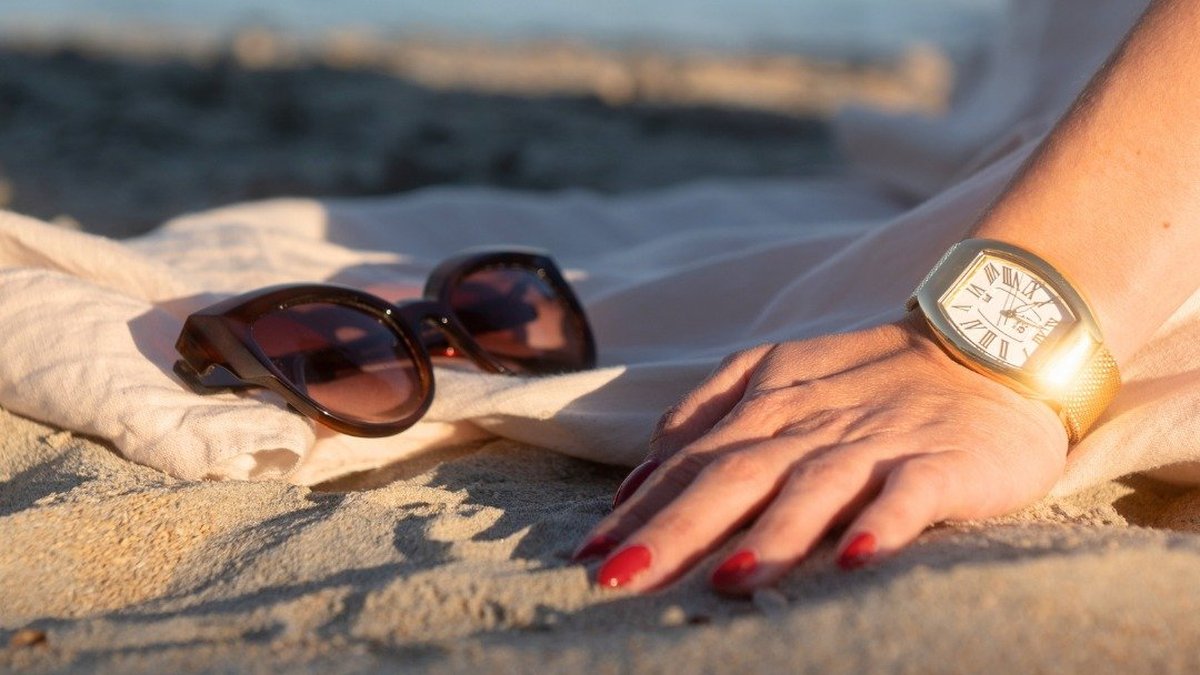 Montre dorée captant un rayon de soleil sur la plage : le principe de la montre solaire