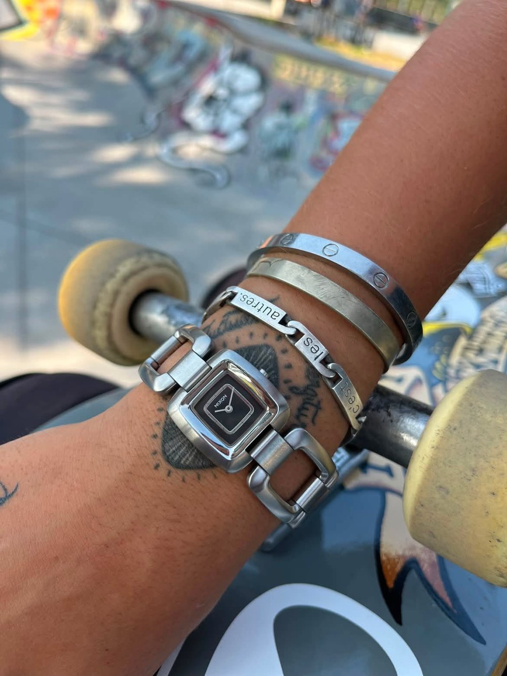 Montre Nixon en acier au poignet d'un skateur au skatepark