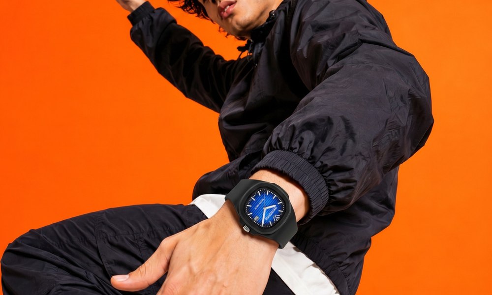 Homme en mouvement sur fond orange, montre de sport a cadran bleu au poignet